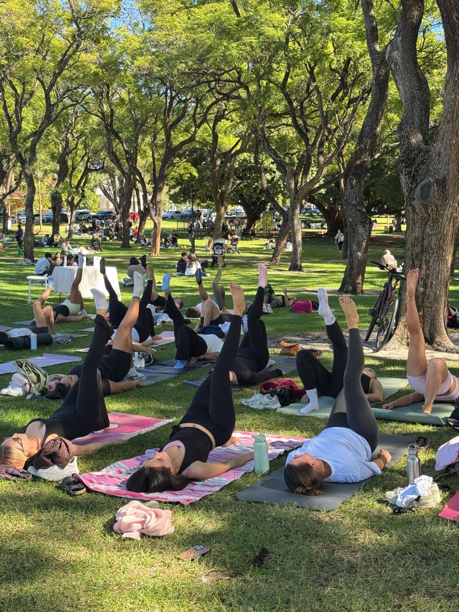 A park full of people mid-class on their mats under the trees