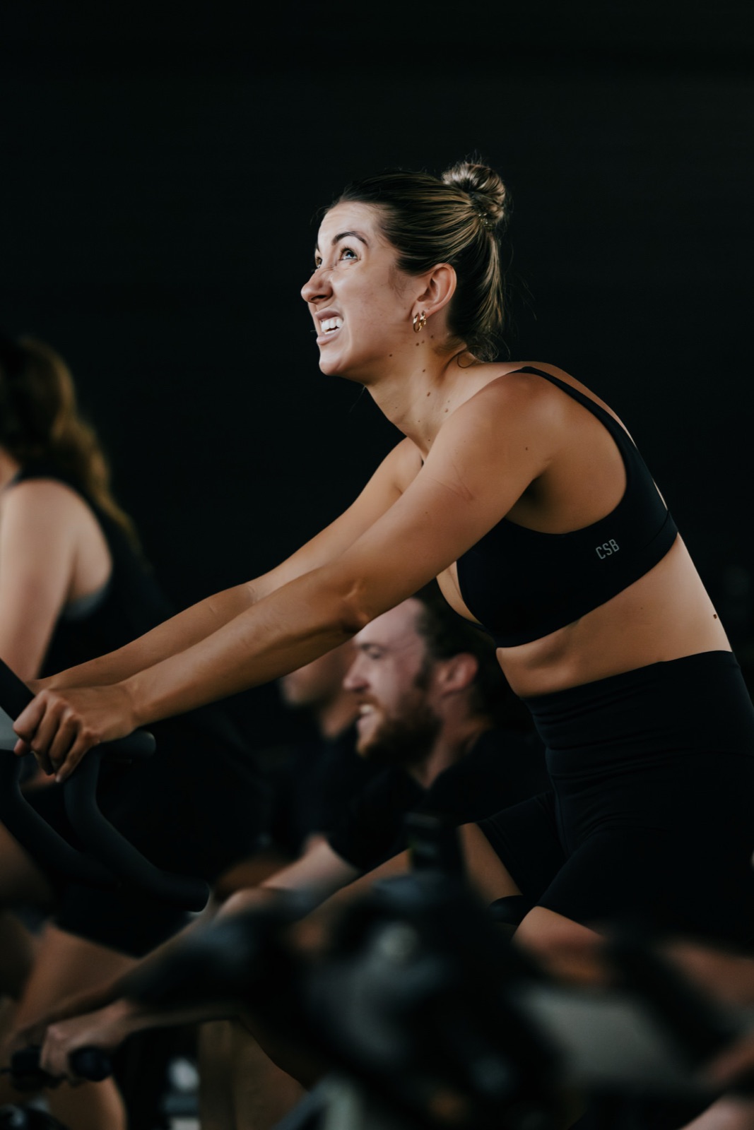 A smiling STRONG member mid-class on the Ride machine